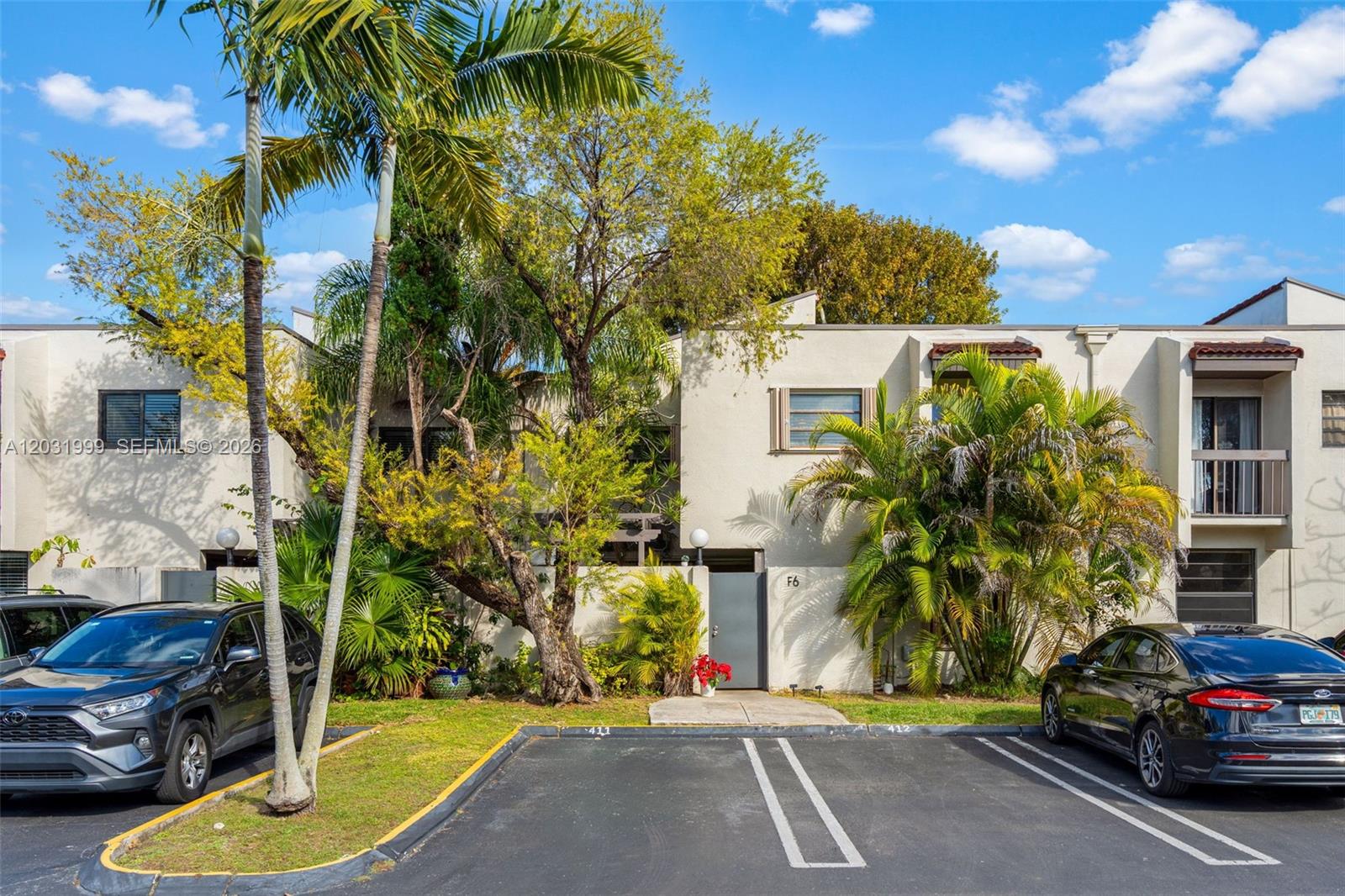 A two-story townhouse exterior features a gray front door, palm trees, and two parked cars — 4726 SW 67th Ave # F6, Miami FL 33155, MIAMI, FL