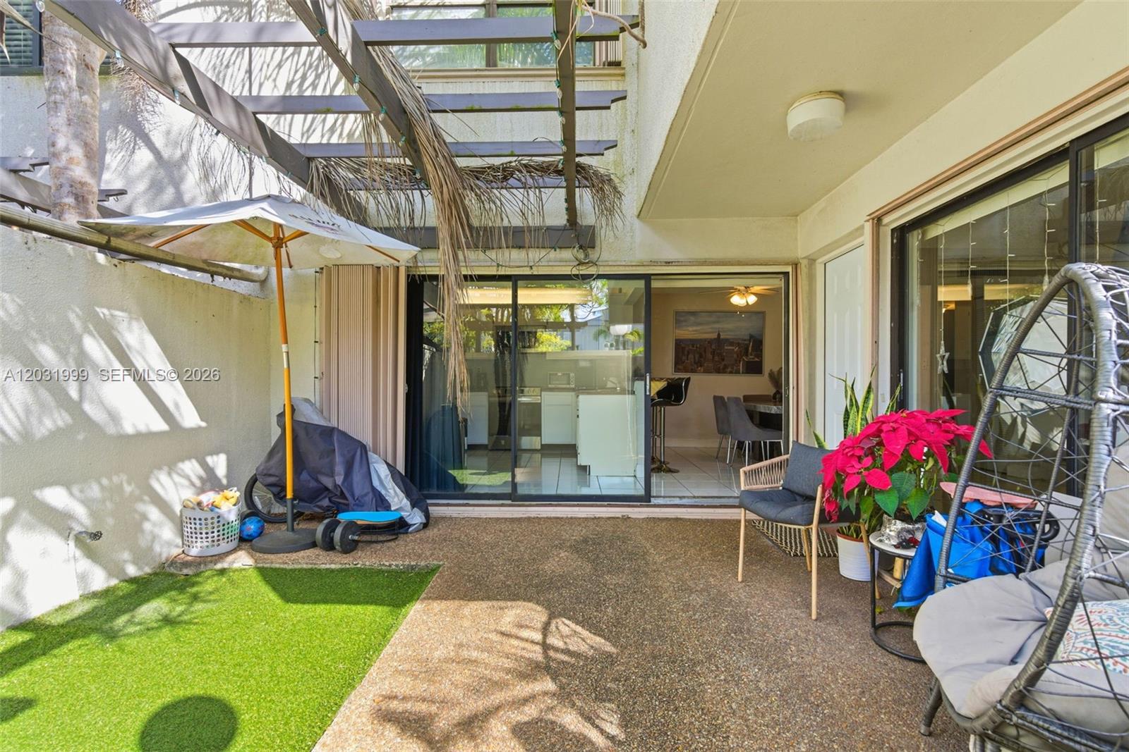 A patio features a pergola, artificial turf, a hanging chair, and sliding glass doors — 4726 SW 67th Ave # F6, Miami FL 33155, MIAMI, FL