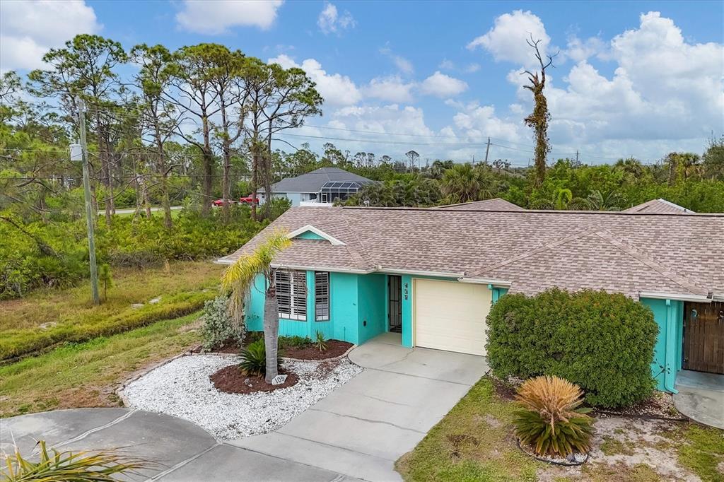 An exterior view of a turquoise single-story house with a concrete driveway and shingled roof — 255 BOUNDARY BOULEVARD UNIT 105, ROTONDA WEST, FL