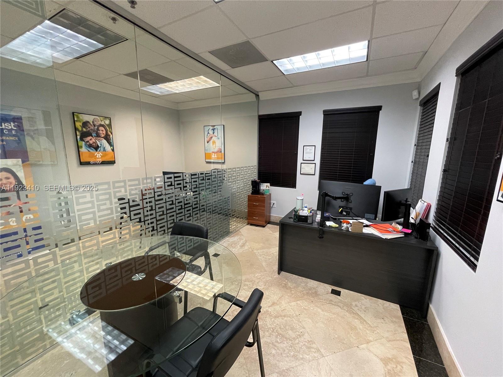 An office space features a glass-walled conference area, a dark desk, and tile flooring — 2893 Executive Park Dr # 104, Weston FL 33331, WESTON, FL