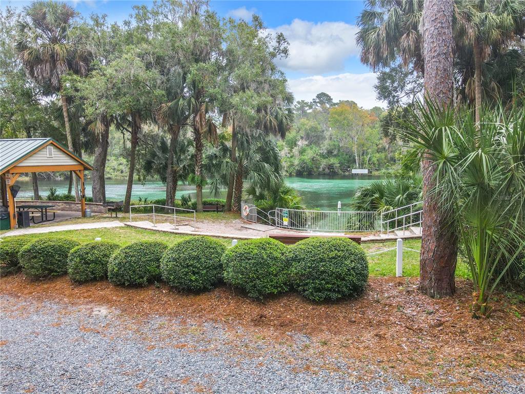 A park area features a pavilion, manicured shrubs, and a fenced walkway leading to a river — 19811 SW 95TH STREET, DUNNELLON, FL
