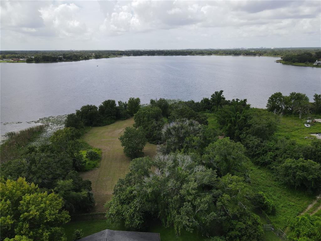 An aerial view shows a grassy lot extending toward a large lake with surrounding trees — DOBSON STREET, ORLANDO, FL