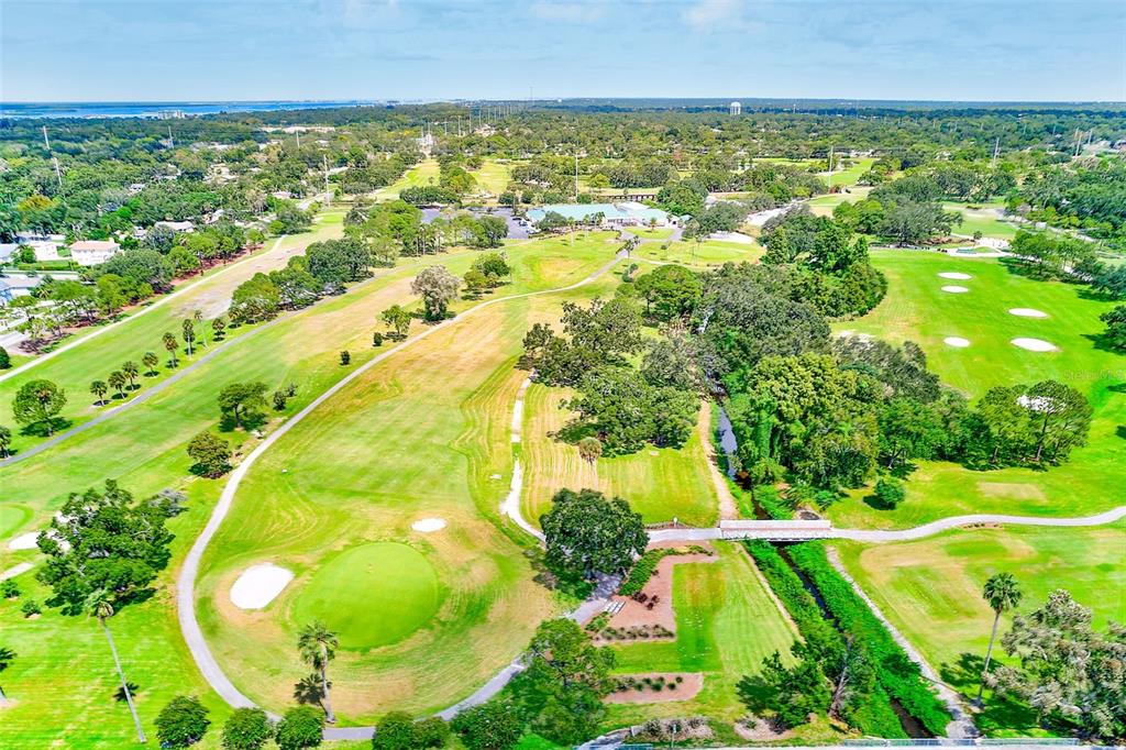 An aerial view shows a golf course with green fairways, sand traps, and surrounding trees — 1329 DREW STREET UNIT 6, CLEARWATER, FL