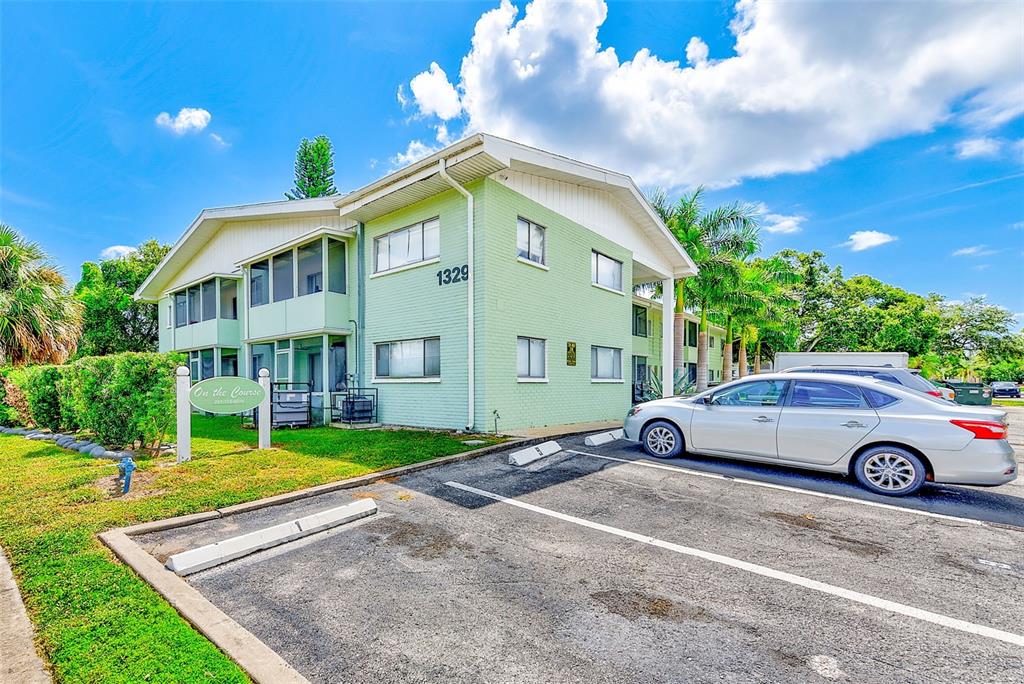A two-story light green apartment building with a parking lot in the foreground — 1329 DREW STREET UNIT 6, CLEARWATER, FL