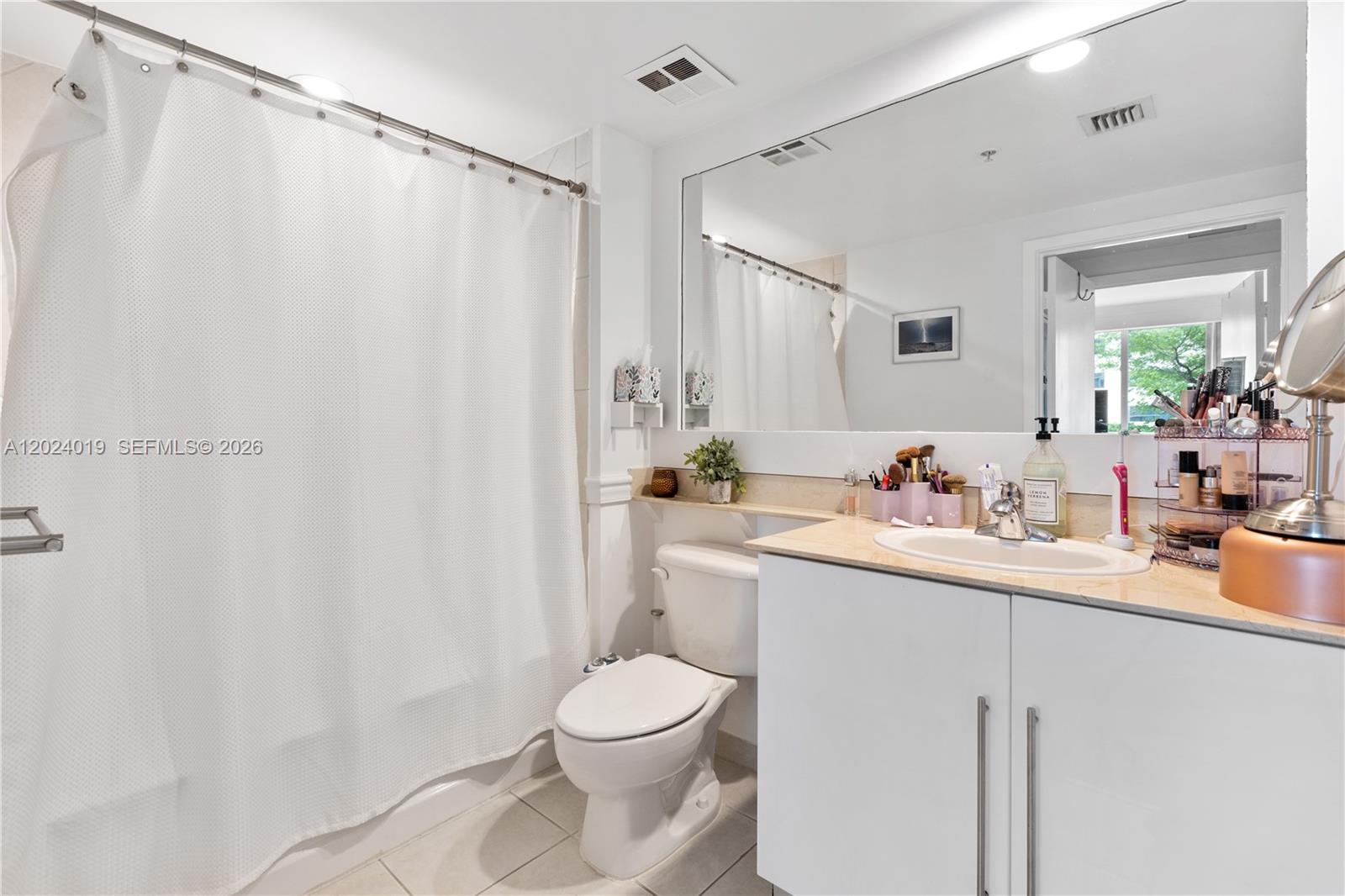 A bathroom features a white vanity, a toilet, and a shower with a white curtain — 335 S Biscayne Blvd # 802, Miami FL 33131, MIAMI, FL