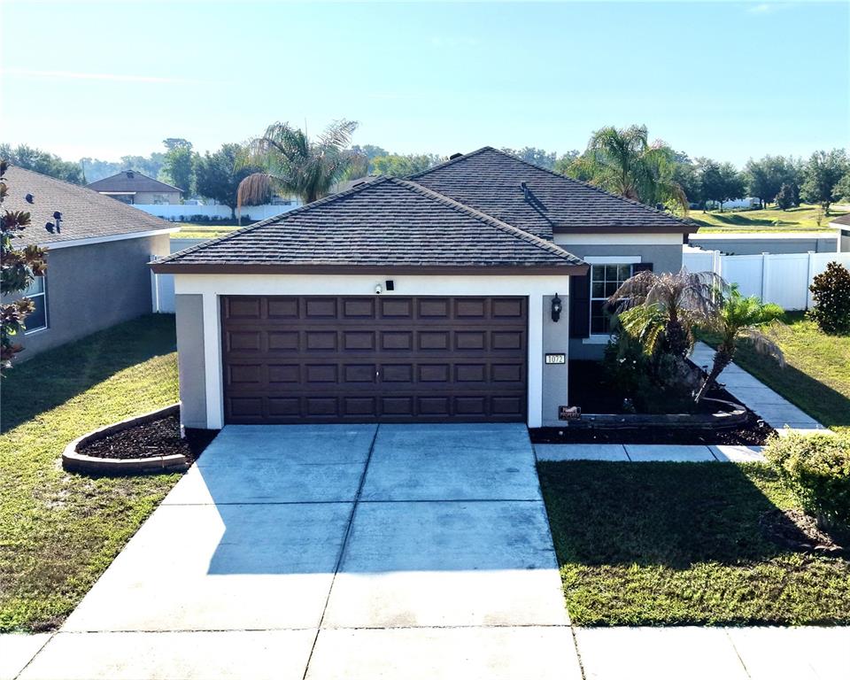 A single-story house with a brown garage door, dark roof, and a concrete driveway — 1072 HILL FLOWER DRIVE, BROOKSVILLE, FL
