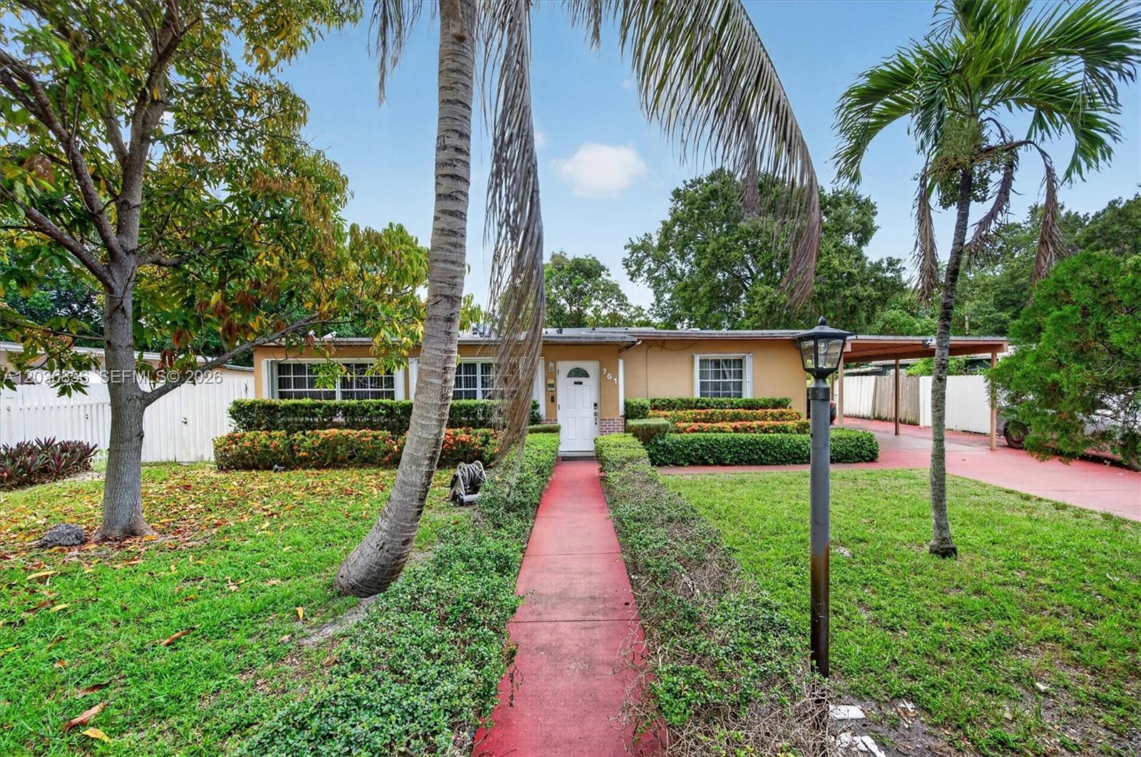 A single-story house with a red walkway, manicured hedges, and palm trees in the front yard — 761 NE 139th St, North Miami FL 33161, NORTH MIAMI, FL