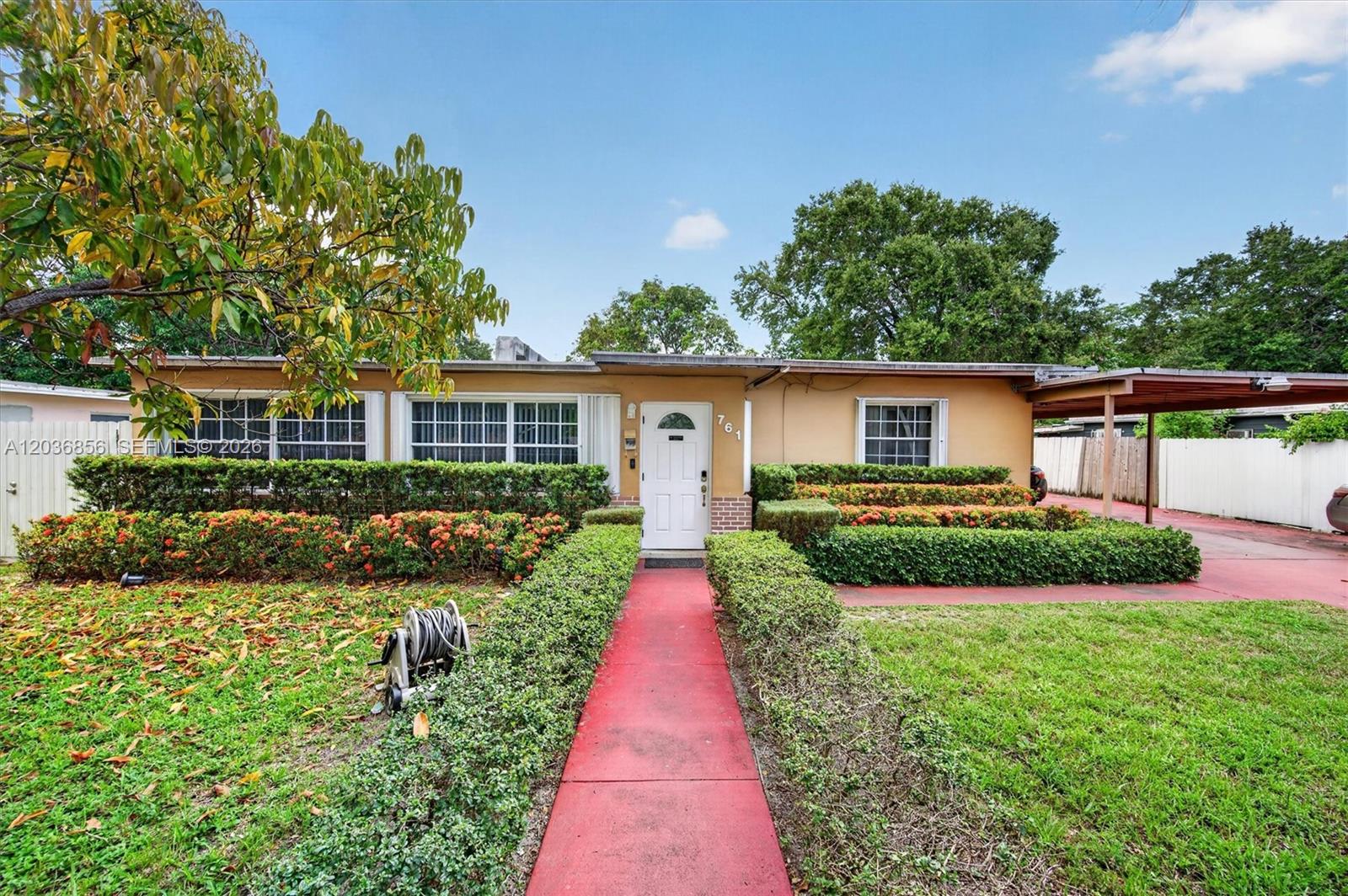 A single-story house features a red walkway, manicured hedges, and a covered carport — 761 NE 139th St, North Miami FL 33161, NORTH MIAMI, FL