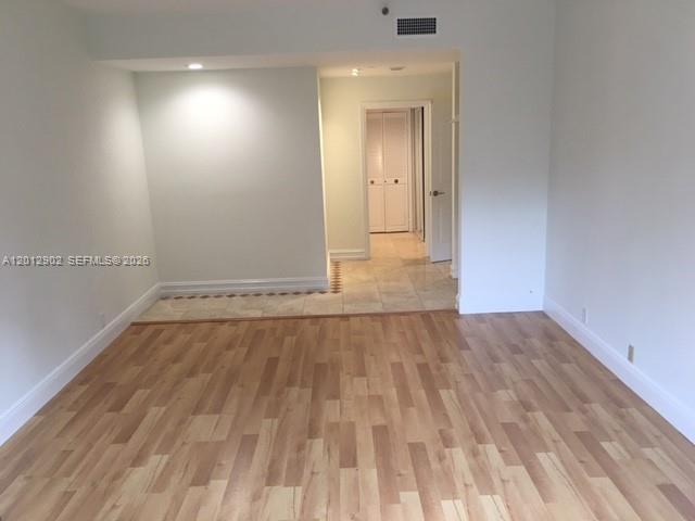 An interior view of a room with light wood flooring and a tiled entryway — 151 Crandon Blvd # 128, Key Biscayne FL 33149, KEY BISCAYNE, FL