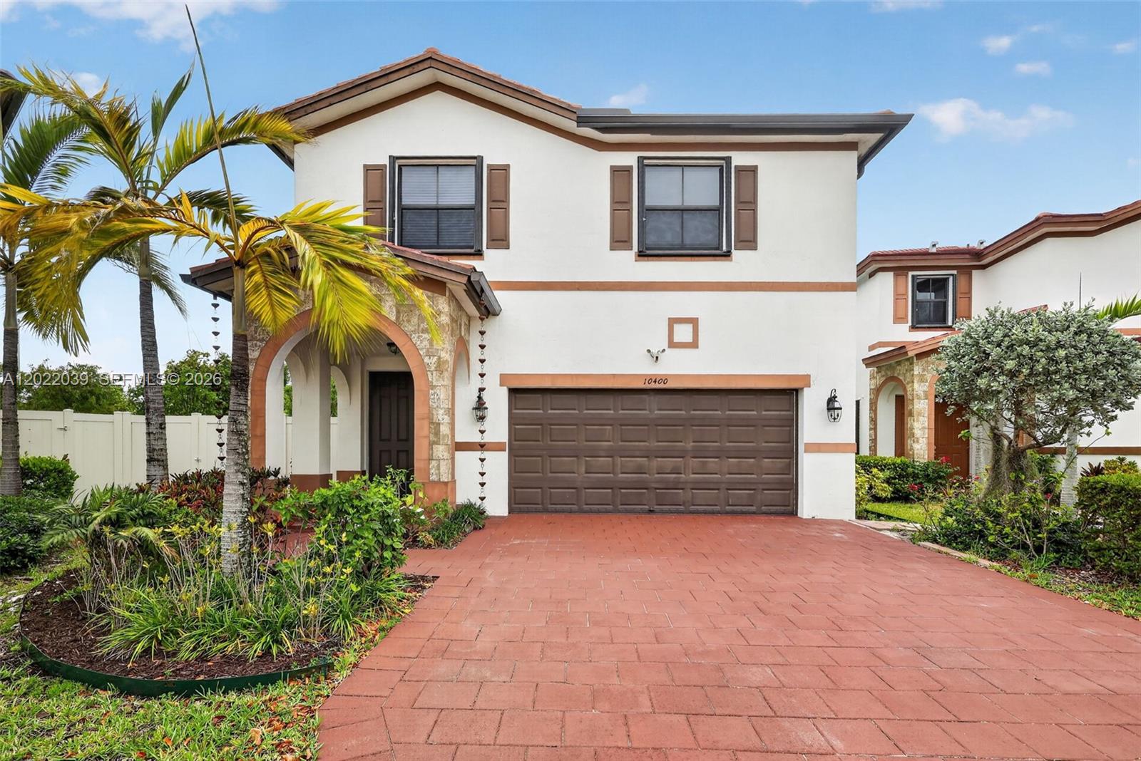 A two-story house features a brown garage door, a stone-accented entryway, and a paved driveway — 10400 W 35 Way, Hialeah FL 33018, HIALEAH, FL