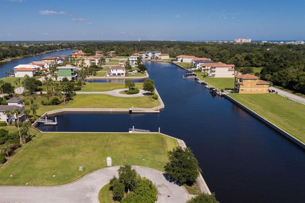 An aerial view shows waterfront residential lots along a canal with several houses nearby — 10 CUTTER COURT, PALM COAST, FL