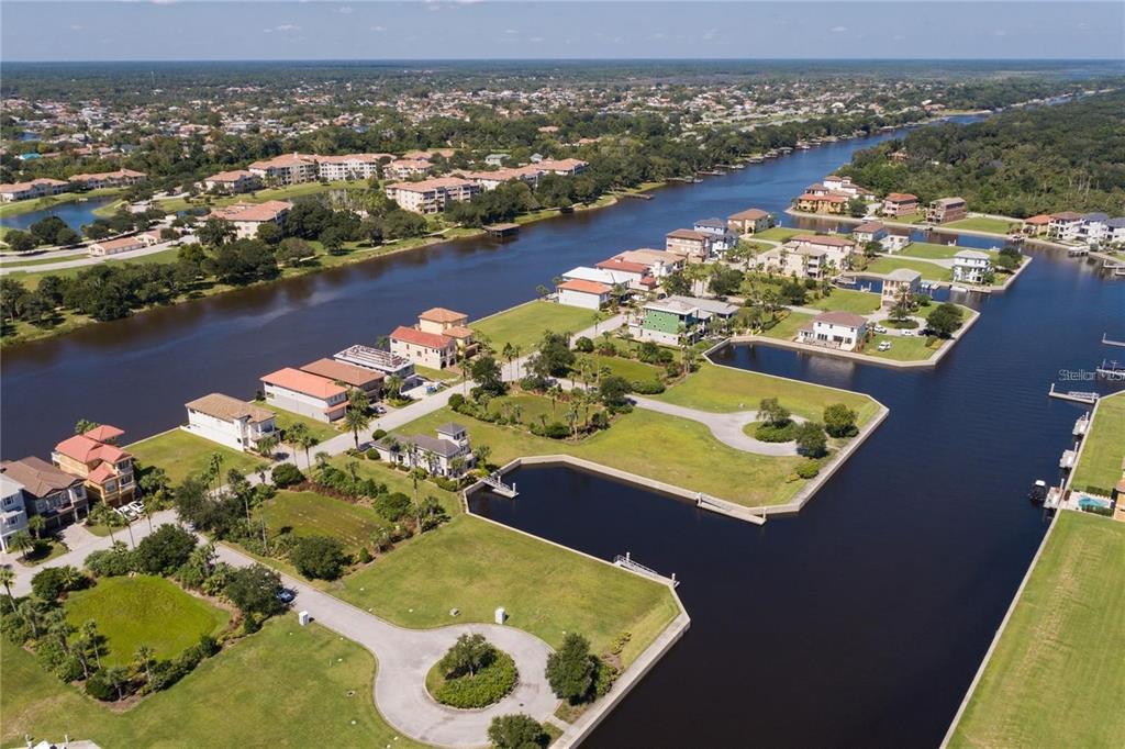 An aerial view shows waterfront houses situated along a canal with green lawns and docks — 10 CUTTER COURT, PALM COAST, FL