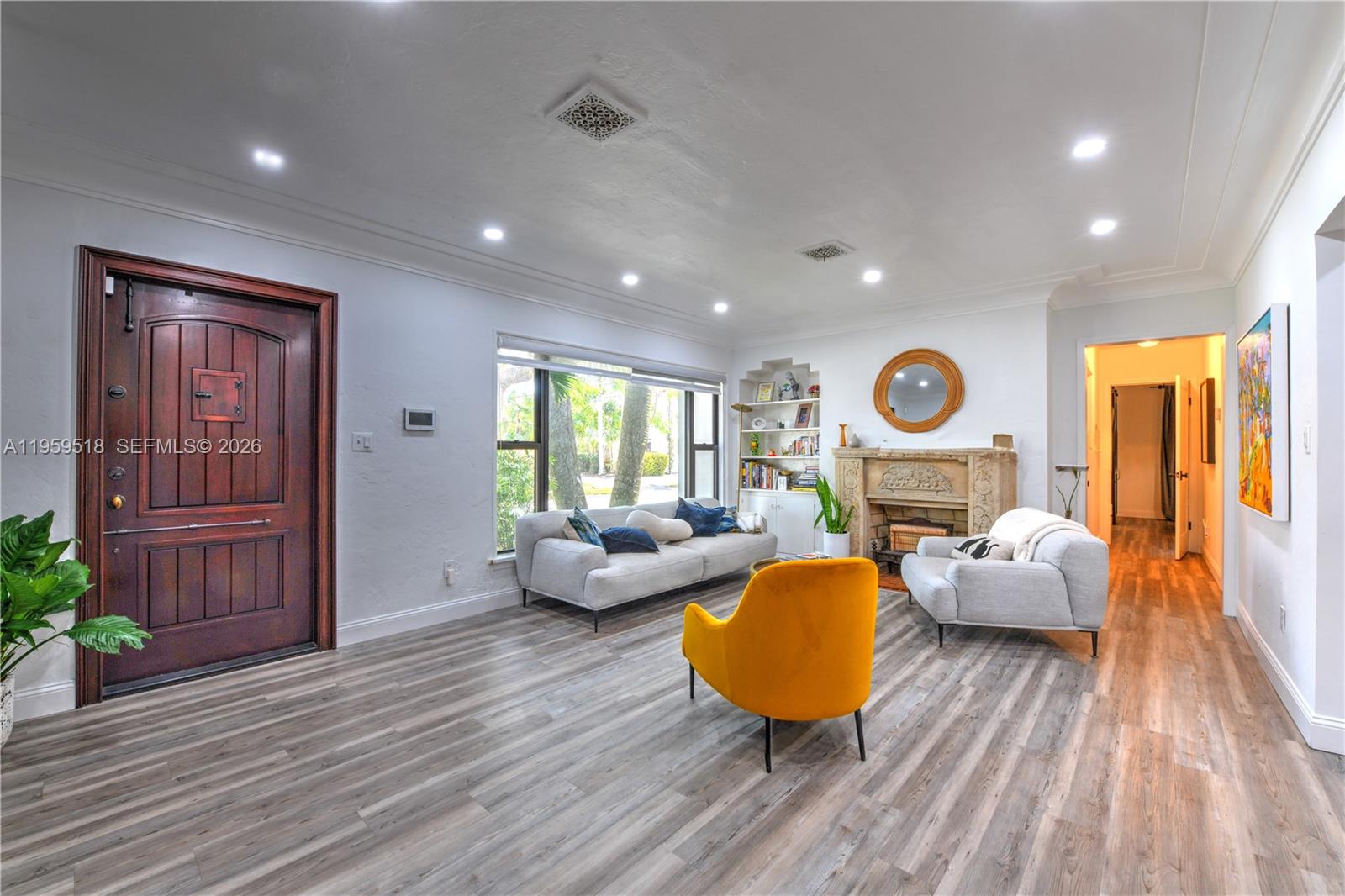 A living room features a wooden front door, fireplace, gray flooring, and modern furniture — 110 N 16th Ave, Hollywood FL 33020, HOLLYWOOD, FL