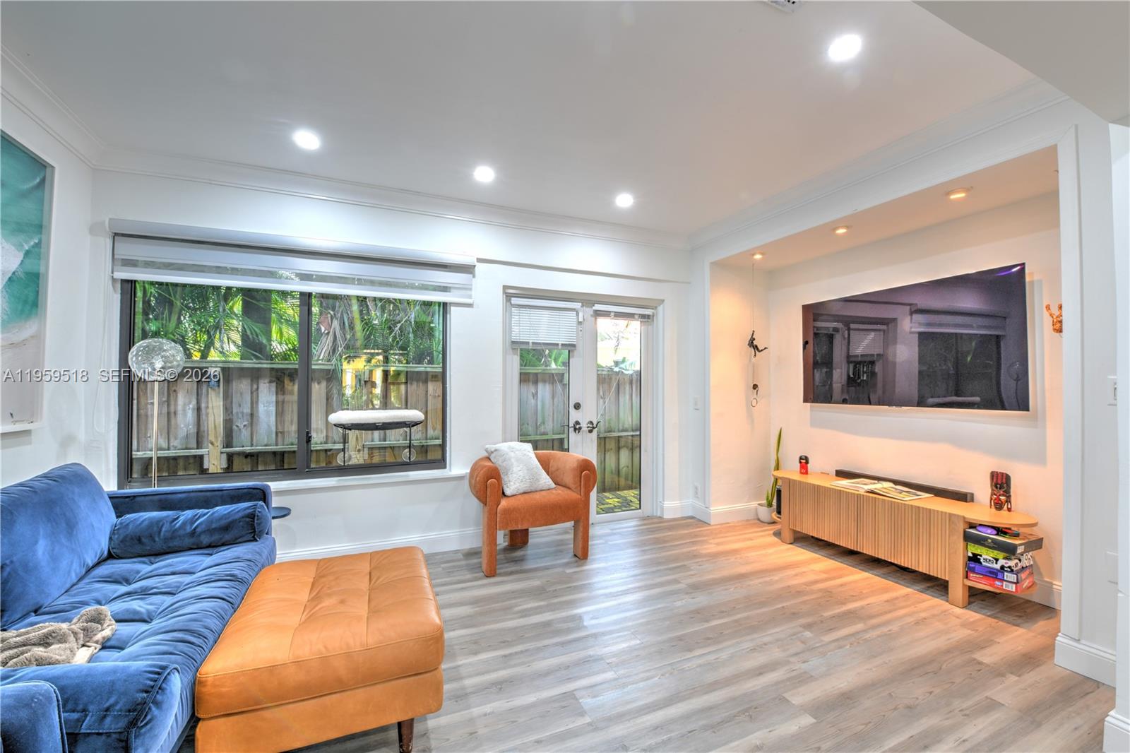 A living room features a blue sofa, orange ottoman, wood media console, and glass doors — 110 N 16th Ave, Hollywood FL 33020, HOLLYWOOD, FL