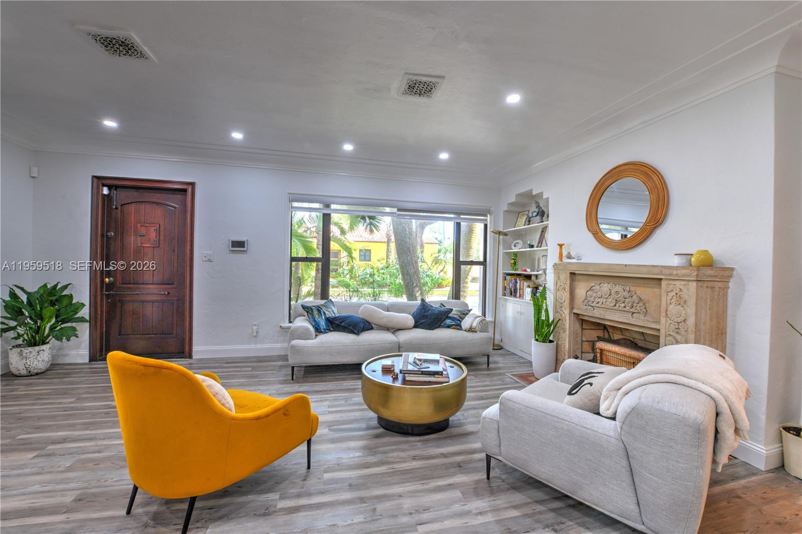 A living room features a fireplace, a yellow armchair, a sofa, and wood-look flooring — 110 N 16th Ave, Hollywood FL 33020, HOLLYWOOD, FL