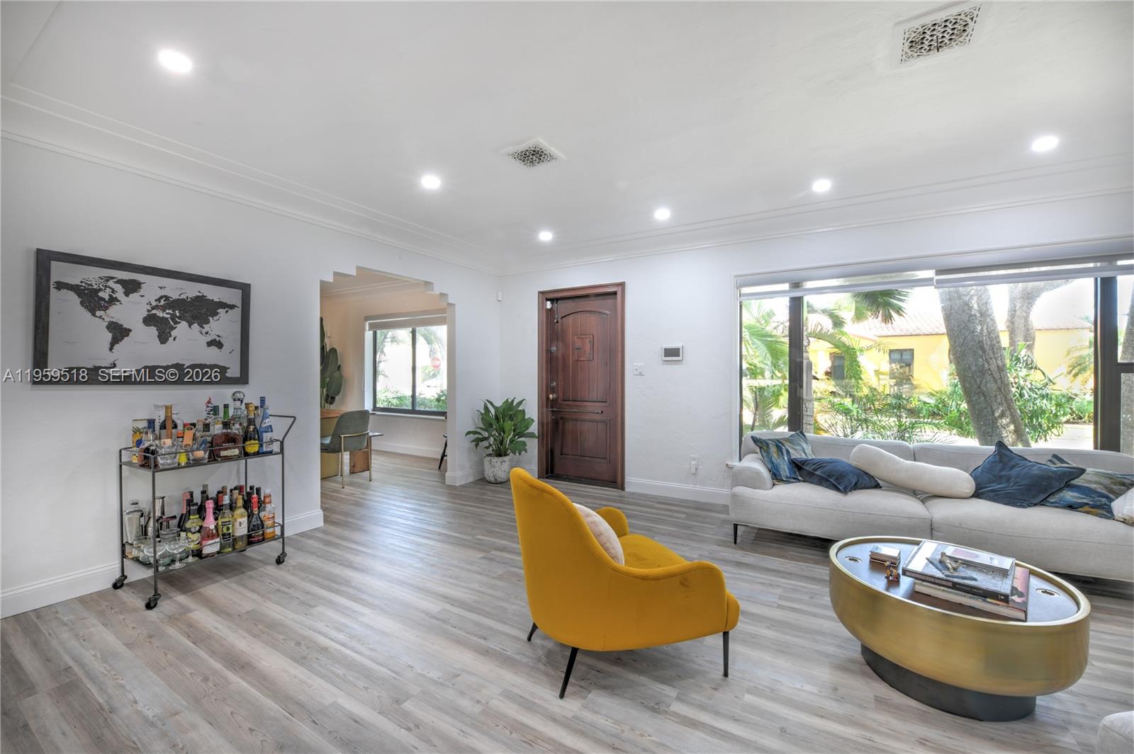 A living room features light wood-look flooring, a yellow armchair, a bar cart, and a sofa — 110 N 16th Ave, Hollywood FL 33020, HOLLYWOOD, FL