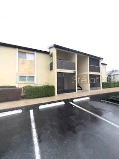 A two-story apartment building exterior features tan siding, screened balconies, and a paved parking lot — 900 LAKE DESTINY ROAD UNIT B, ALTAMONTE SPRINGS, FL