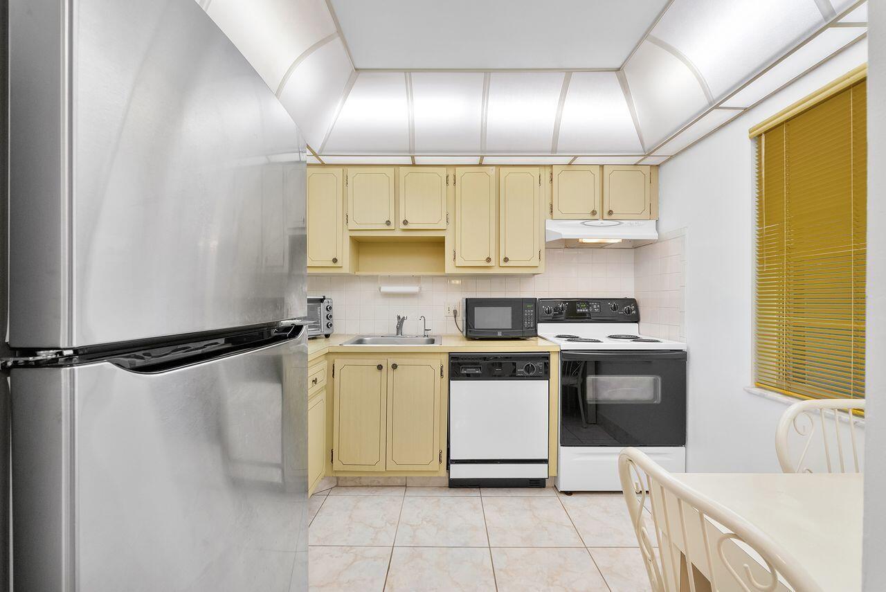 A kitchen with yellow cabinets, stainless steel appliances, and a tray ceiling with recessed lighting — 7807 Golf Cir Drive # 308, Margate FL 33063, MARGATE, FL