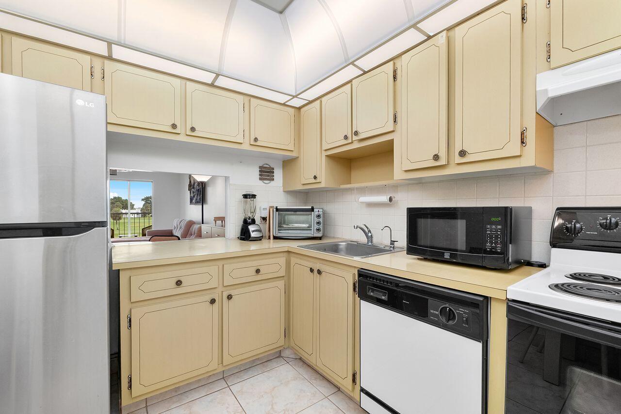 A kitchen with light-colored cabinets, stainless steel appliances, and a pass-through window to a room — 7807 Golf Cir Drive # 308, Margate FL 33063, MARGATE, FL