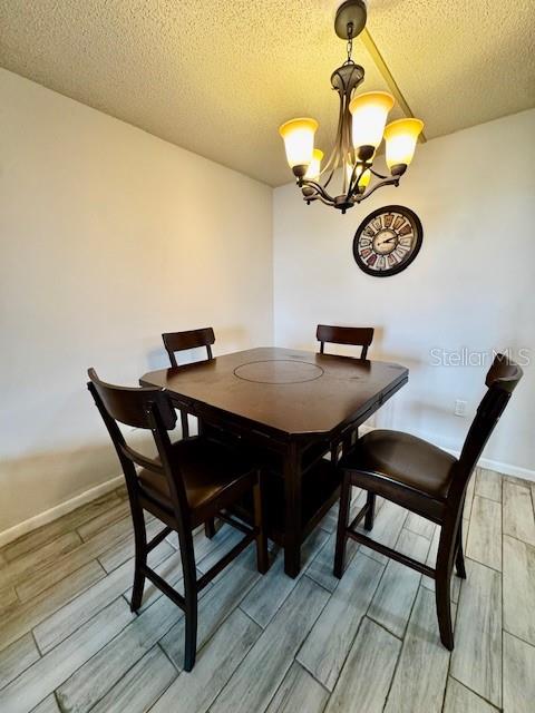 A dining area features a square wooden table, four chairs, a chandelier, and a wall clock — 3006 CARING WAY UNIT 301, PORT CHARLOTTE, FL