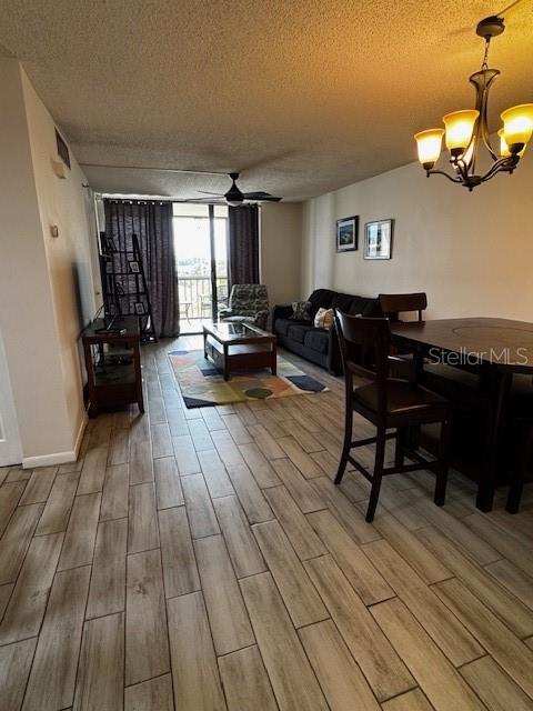 This living and dining area features wood-look tile flooring, a ceiling fan, and a chandelier — 3006 CARING WAY UNIT 301, PORT CHARLOTTE, FL
