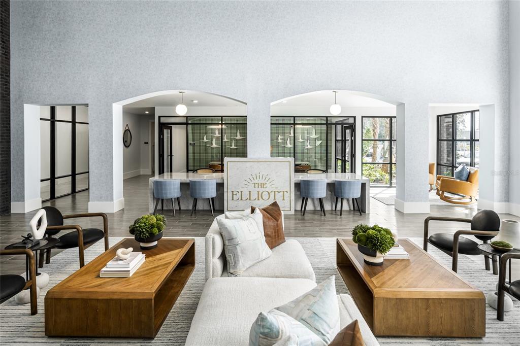 A modern apartment lobby features a central reception desk, lounge seating, and large arched openings — 20191 SABAL PALM COURT UNIT C2, LAND O LAKES, FL
