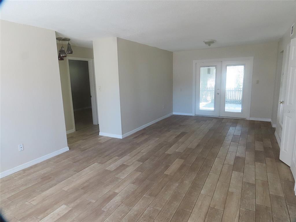 A living room with light-colored walls, wood-look tile flooring, and glass French doors — 749 SEMINOLE AVENUE, LONGWOOD, FL