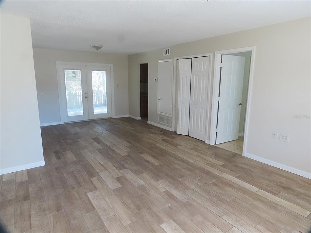 An empty room with light-colored walls, wood-look tile flooring, French doors, and several interior doors — 749 SEMINOLE AVENUE, LONGWOOD, FL