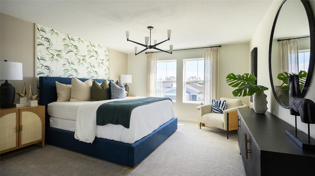 A bedroom features a blue upholstered bed, palm-patterned wallpaper, and a large round wall mirror — 9098 BELLEVIEW FOREST PASS, DADE CITY, FL
