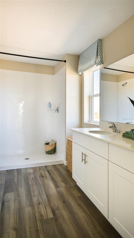 A bathroom features a walk-in shower, white vanity with a sink, and wood-look flooring — 9098 BELLEVIEW FOREST PASS, DADE CITY, FL