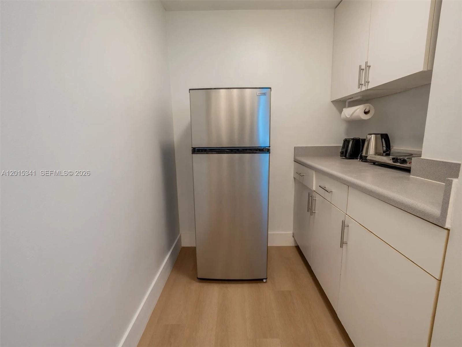 A kitchen features white cabinets, a gray countertop, and a stainless steel refrigerator — 5445 Collins Ave # 1718, Miami Beach FL 33140, MIAMI BEACH, FL