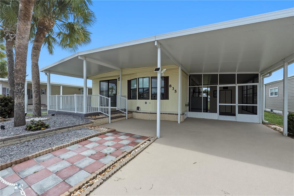 A manufactured home with a carport, screened-in porch, and a paved walkway — 2100 KINGS HIGHWAY UNIT 835, PORT CHARLOTTE, FL