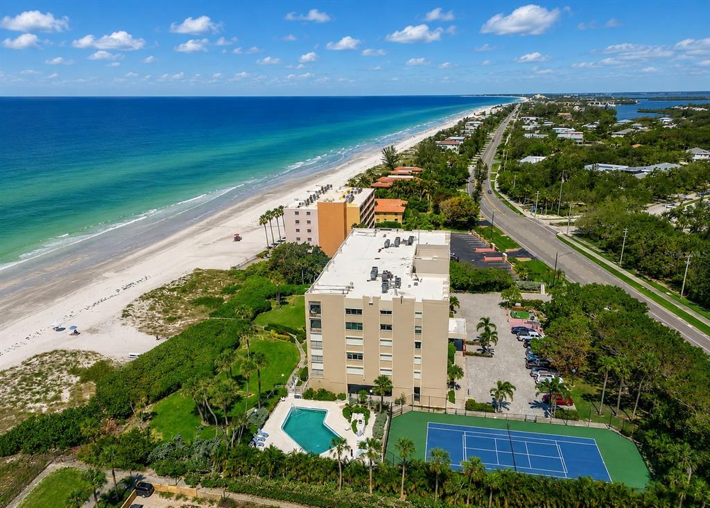 An aerial view shows a beachfront condominium building with a pool and tennis court — 2675 GULF OF MEXICO DRIVE UNIT 203, LONGBOAT KEY, FL