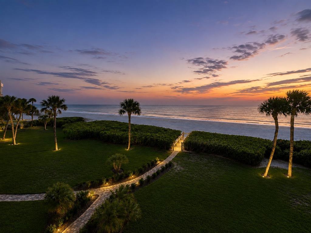 A grassy lawn with palm trees leads to a sandy beach and the ocean — 2675 GULF OF MEXICO DRIVE UNIT 203, LONGBOAT KEY, FL