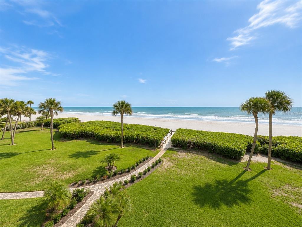 A living room with a white sofa, recliner, chandelier, and a balcony overlooking the ocean — 2675 GULF OF MEXICO DRIVE UNIT 203, LONGBOAT KEY, FL