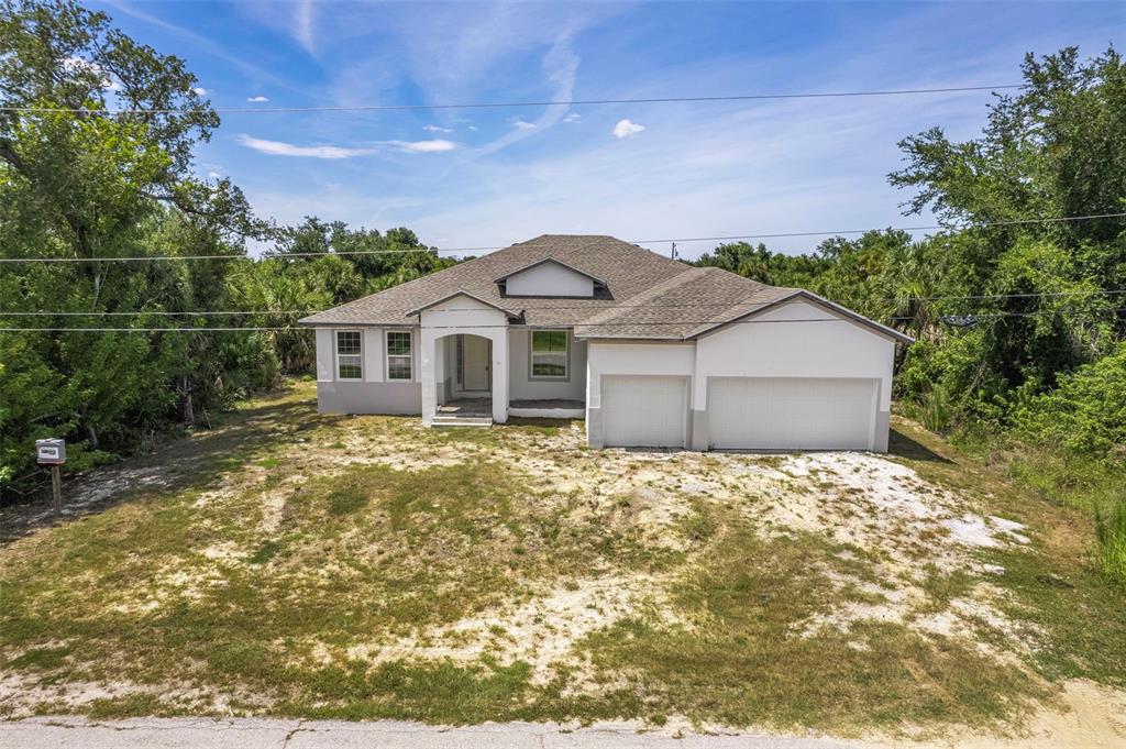 A single-story house with a two-car garage and an unfinished sandy yard — 13298 HIGH SPRINGS AVENUE, PORT CHARLOTTE, FL