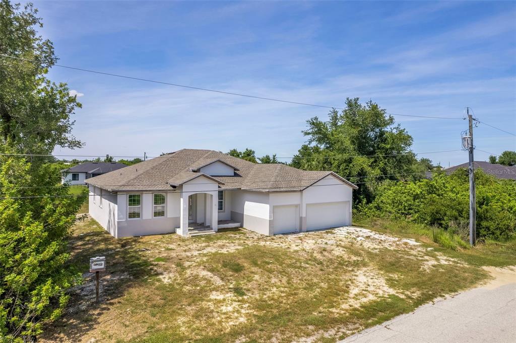 An exterior view of a single-story house with a two-car garage and unfinished landscaping — 13298 HIGH SPRINGS AVENUE, PORT CHARLOTTE, FL