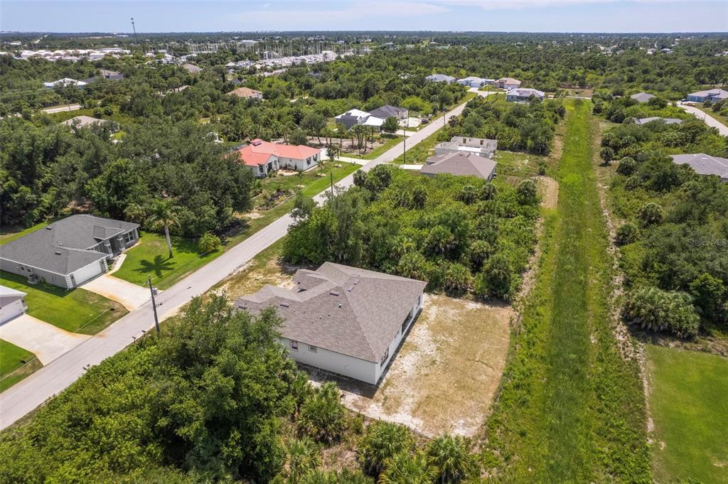 An aerial view shows a suburban neighborhood with houses, paved roads, and wooded lots — 13298 HIGH SPRINGS AVENUE, PORT CHARLOTTE, FL