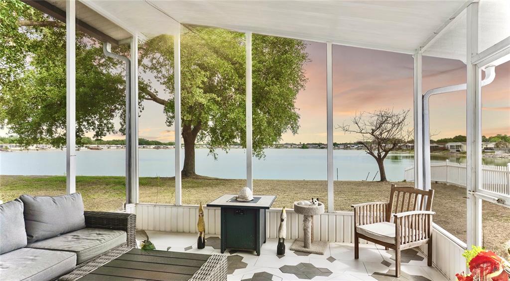A screened-in porch features gray furniture, a small fire pit, and a view of water — 9426 STAR GAZER LANE, RIVERVIEW, FL