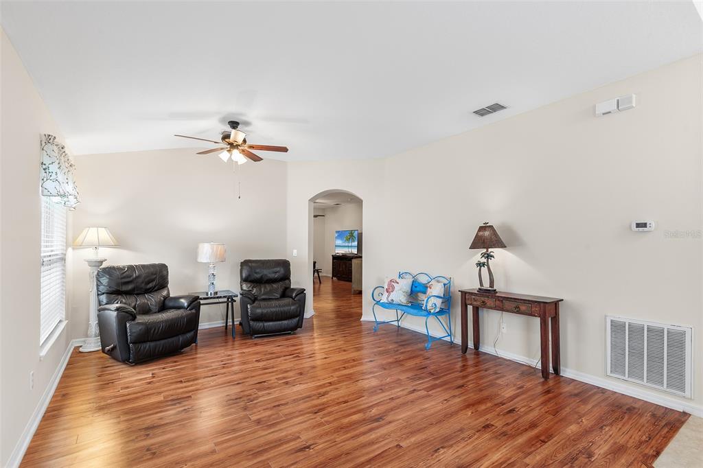 A living room features wood-look flooring, beige walls, two leather recliners, and a metal bench — 4134 BEDFORD AVENUE, WINTER HAVEN, FL