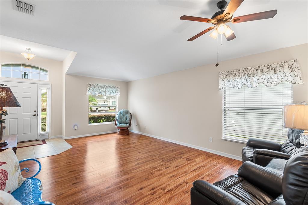 A living room with wood-look flooring, a ceiling fan, and two windows with valances — 4134 BEDFORD AVENUE, WINTER HAVEN, FL