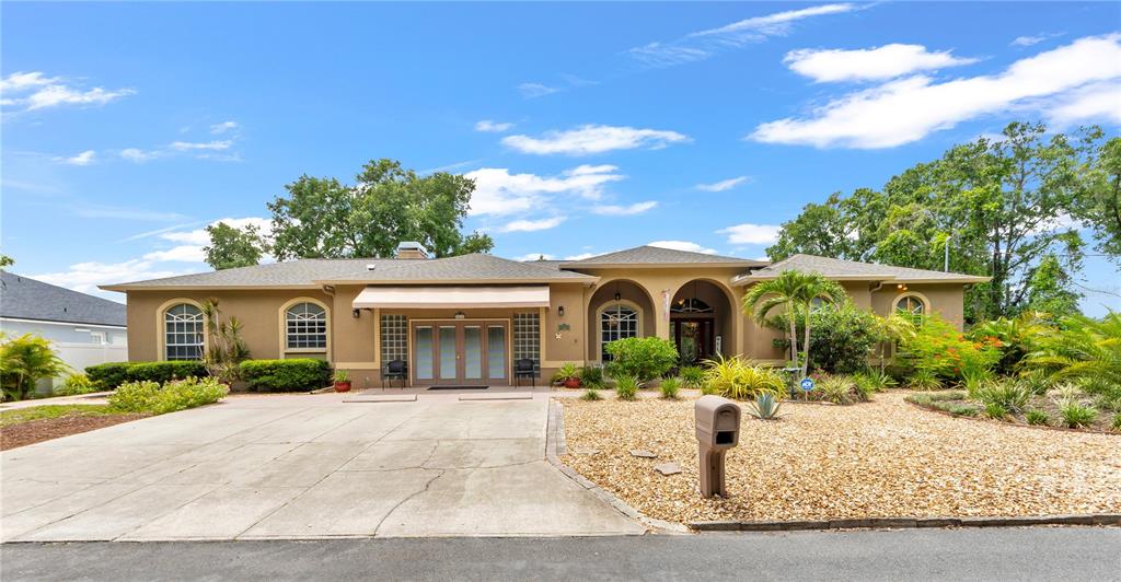 A single-story house with a beige stucco exterior, a concrete driveway, and a gravel front yard — 7816 MARIGOLD AVENUE, TAMPA, FL