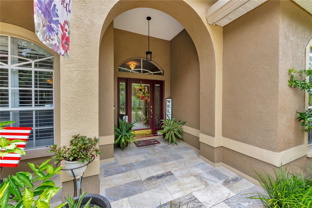 A covered entryway features a tiled floor, an arched ceiling, and a red front door — 7816 MARIGOLD AVENUE, TAMPA, FL