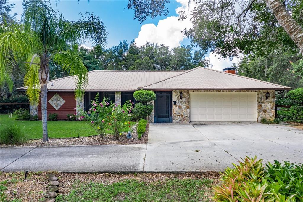 A single-story house with a metal roof, stone accents, and a two-car garage — 1273 SCRUB JAY TRAIL, FROSTPROOF, FL