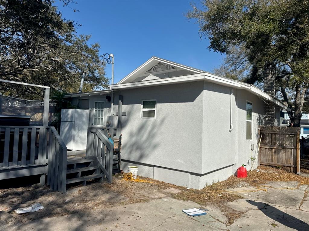 The exterior of a gray stucco house features a wooden deck, stairs, and a chimney — 3740 28TH AVENUE S, ST PETERSBURG, FL