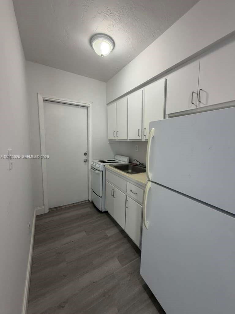 A small galley kitchen features white cabinets, a white refrigerator, and gray wood-look flooring — 1628 SW 7th St # 9, Miami FL 33135, MIAMI, FL