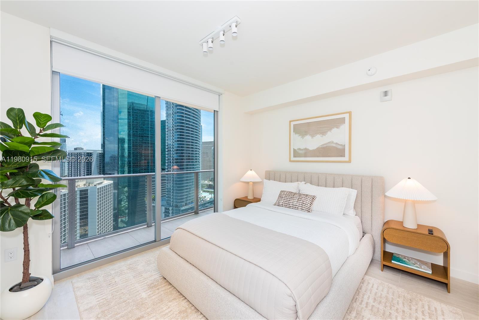 A modern bedroom features a queen bed, two nightstands, and floor-to-ceiling windows overlooking city skyscrapers — 77 SE 5th Street # 3204, Miami FL 33131, MIAMI, FL