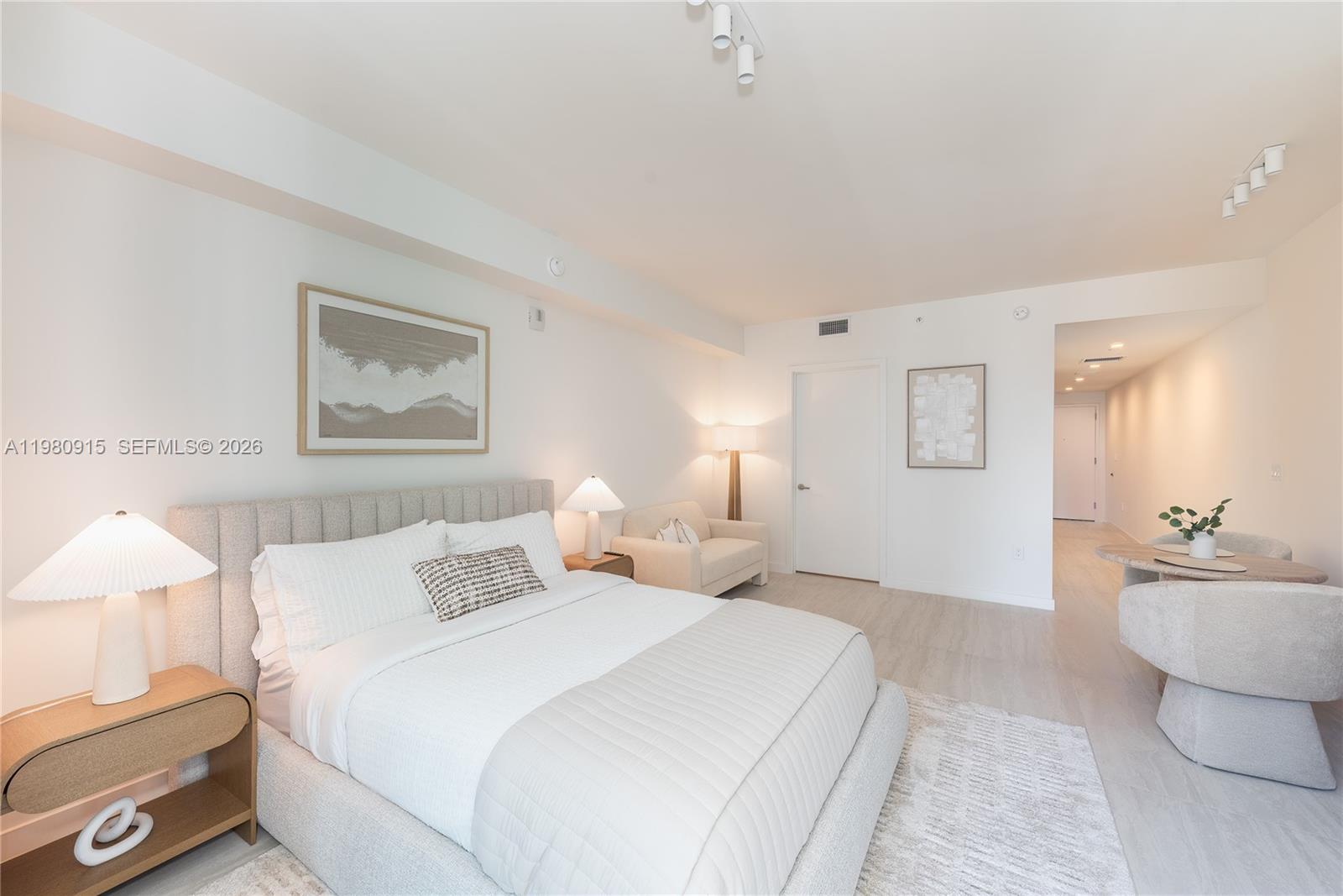 A bedroom features a neutral color palette, a tufted headboard, and a small dining area — 77 SE 5th Street # 3204, Miami FL 33131, MIAMI, FL