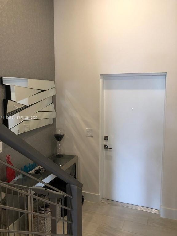 An entryway features a white door, a modern geometric mirror, and a glass console table — 4500 NW 8th Pl, Plantation FL 33317, PLANTATION, FL