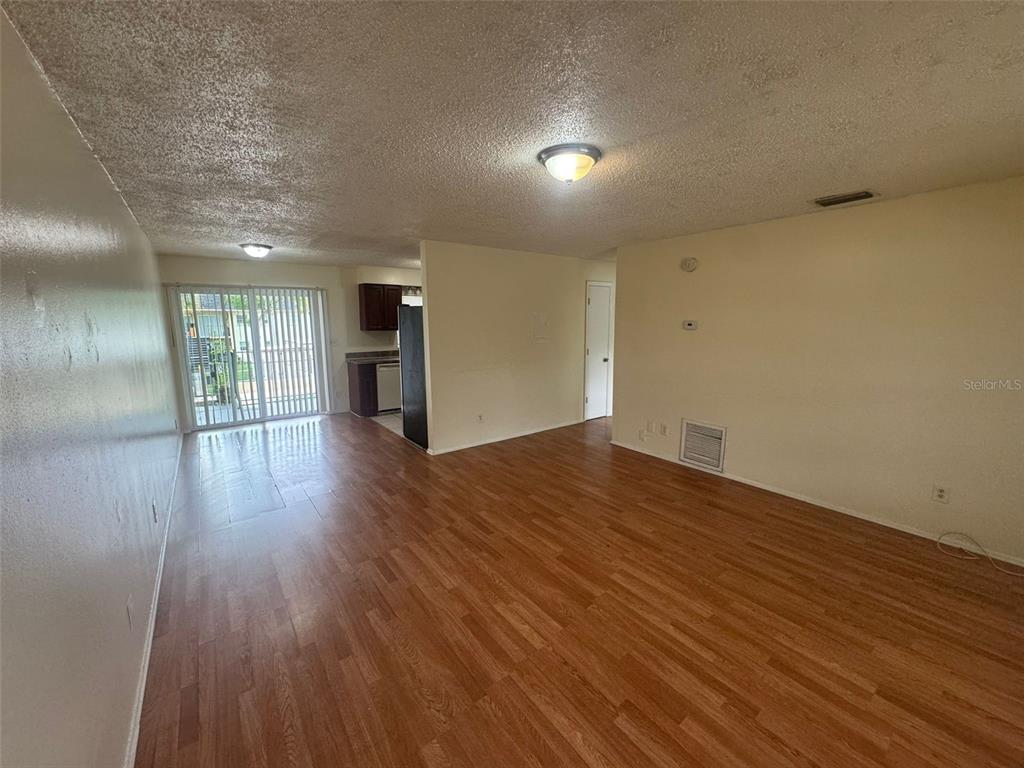 An interior view of a living room with wood-look flooring and a sliding glass door — 2800 E 113TH AVENUE UNIT B1204, TAMPA, FL